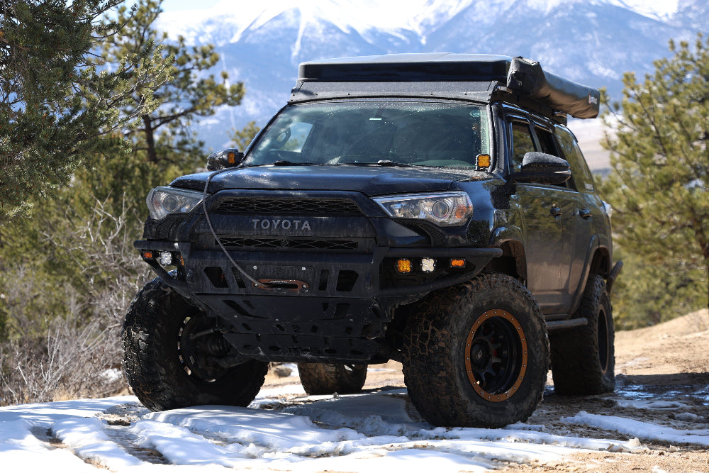 Black Toyota SUV with roof rack in snowy mountainous area