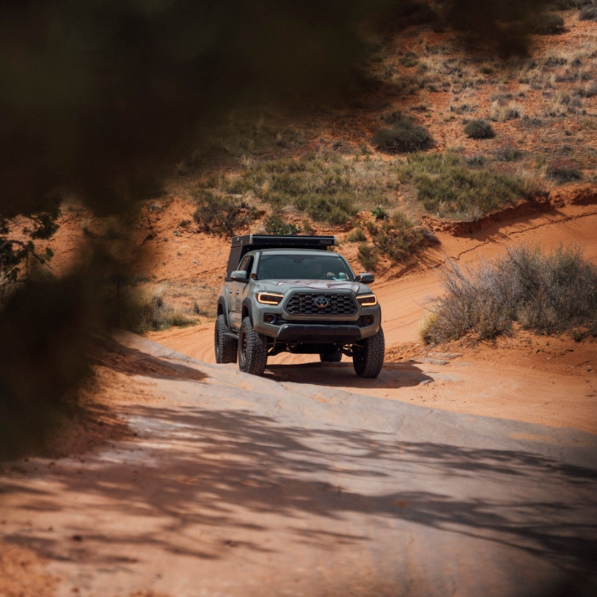 Off-road vehicle driving on a dirt road in a desert landscape