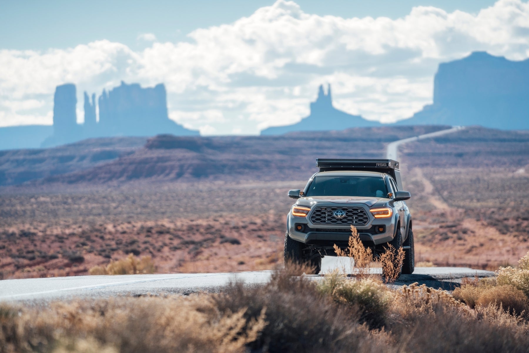 Truck on a desert road with Monument Valley in the background